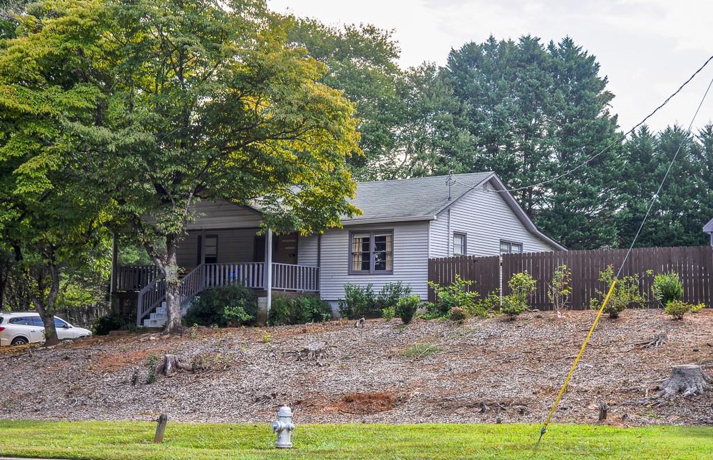 a view of a house with a yard and large trees