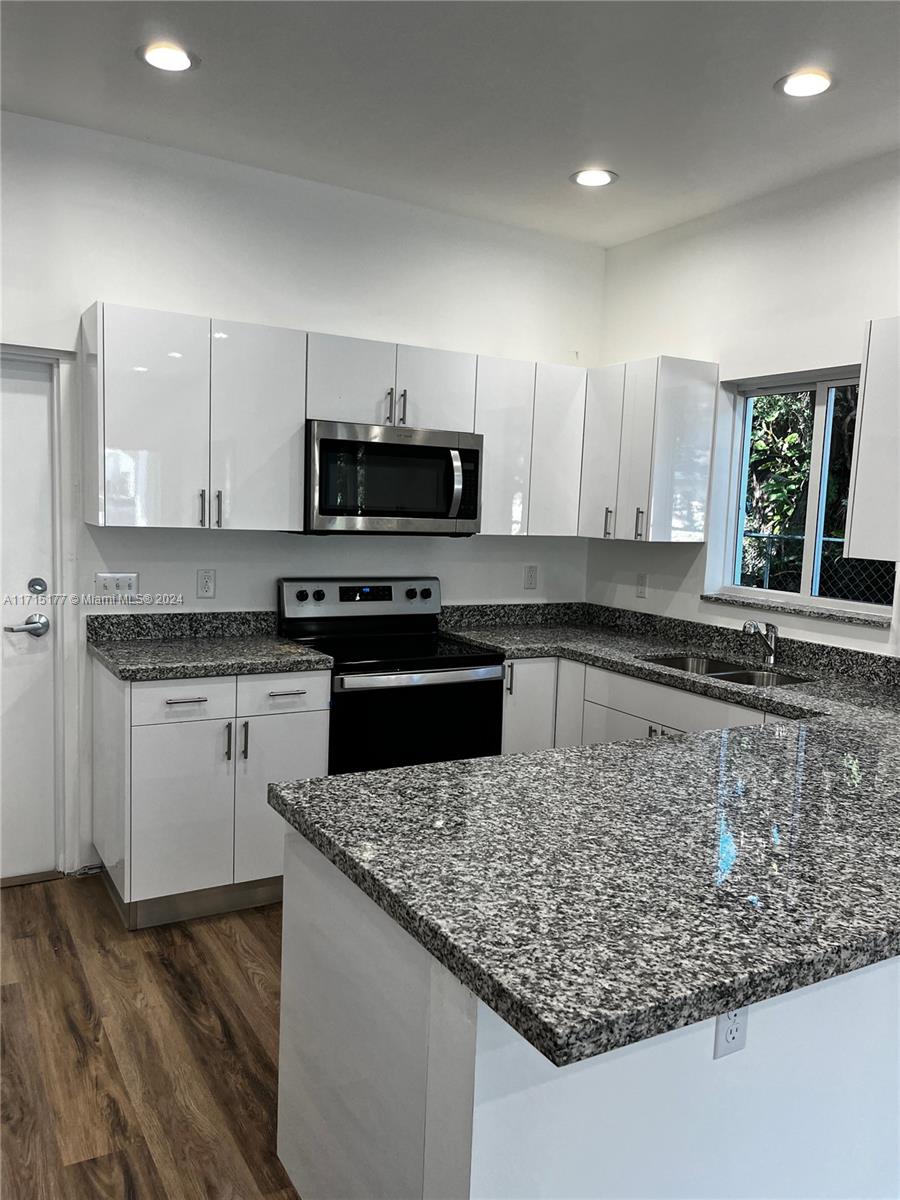 a kitchen with kitchen island granite countertop a sink and a stove top oven