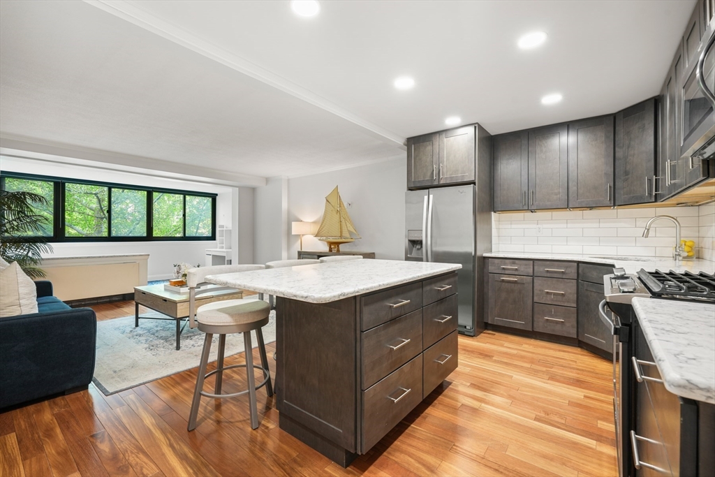 a kitchen with stainless steel appliances kitchen island granite countertop a table chairs sink and cabinets