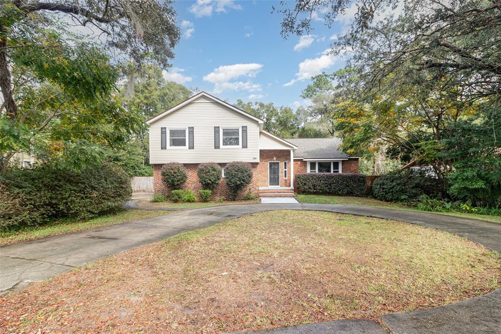 a view of a house with a yard and large tree