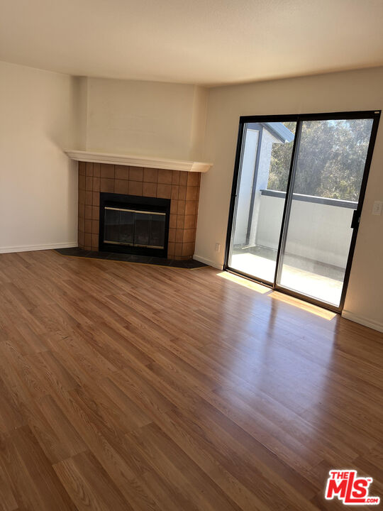 a view of empty room with wooden floor and fireplace