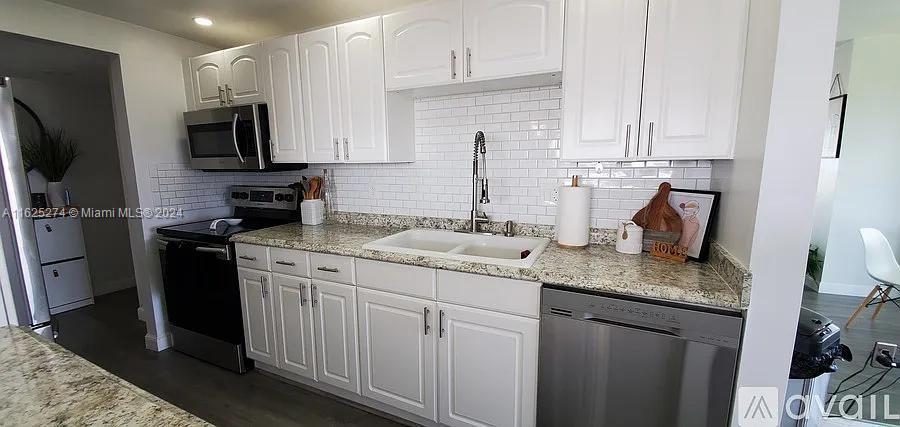 a kitchen with stainless steel appliances granite countertop a sink stove refrigerator and cabinets