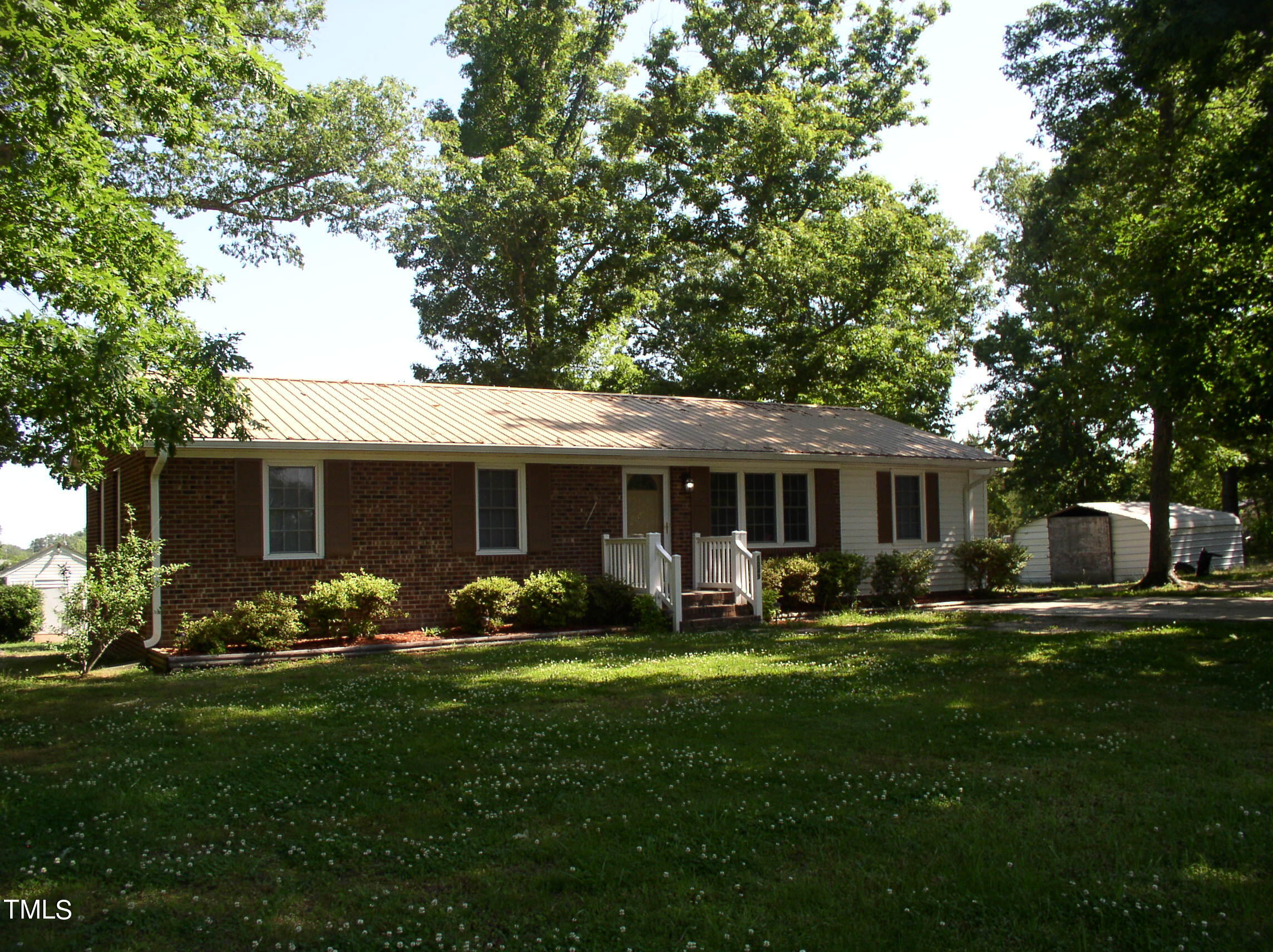 a front view of house with a garden and trees