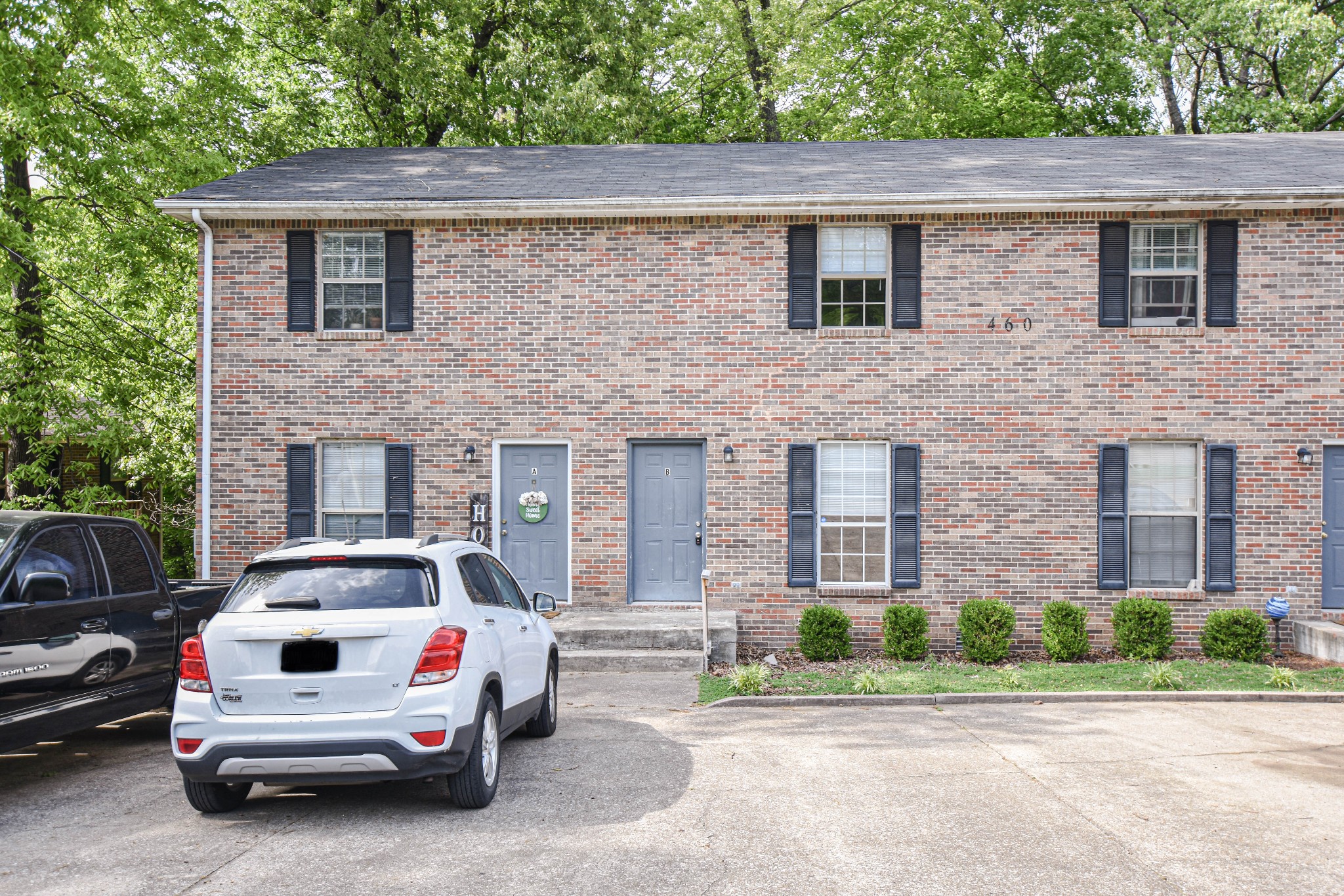 a white car parked in front of a brick house