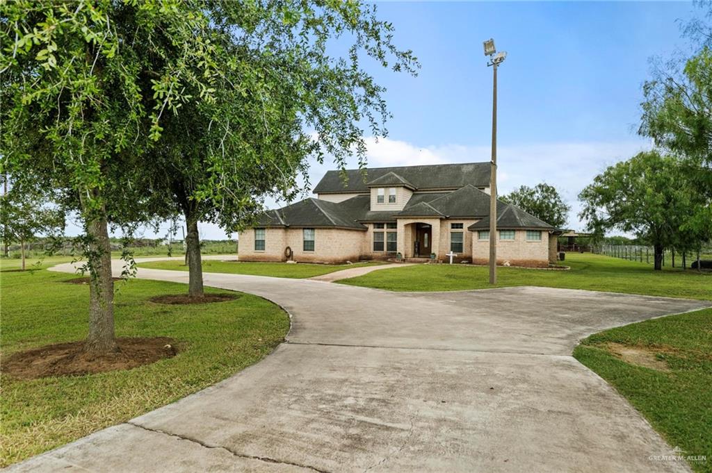 a view of a house with a big yard plants and large trees