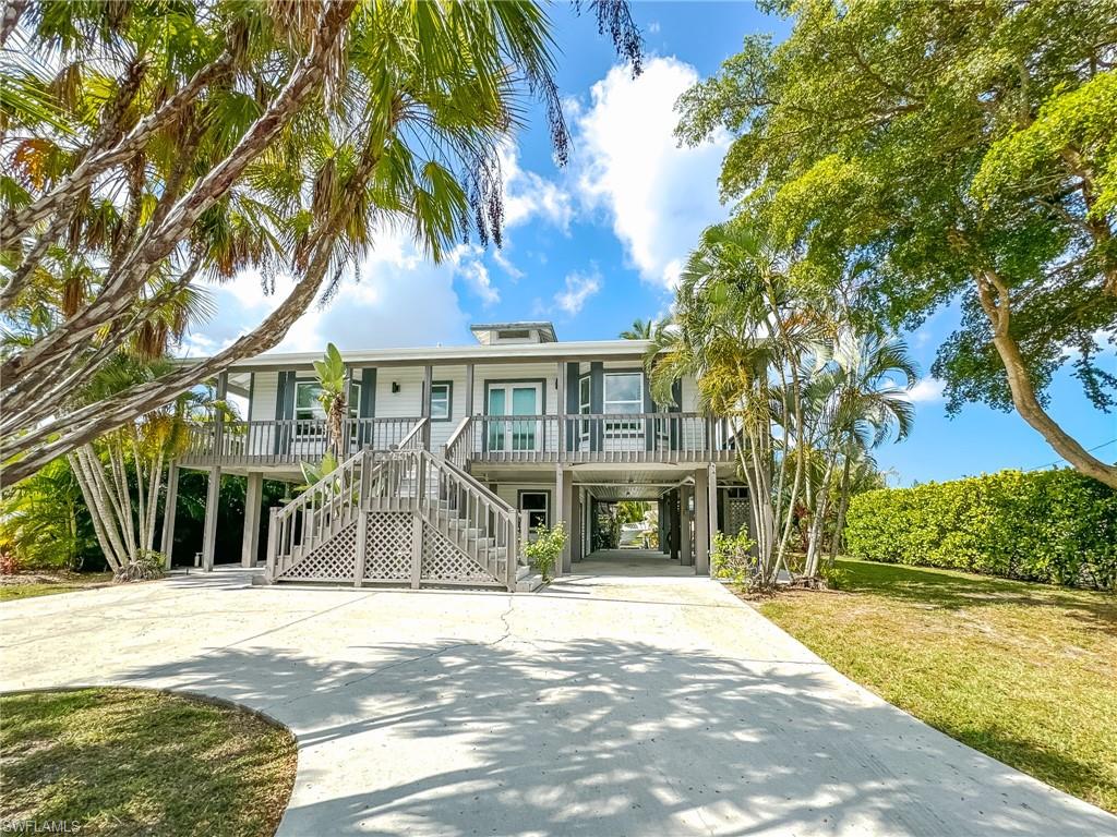 a view of a white house next to a yard with palm trees