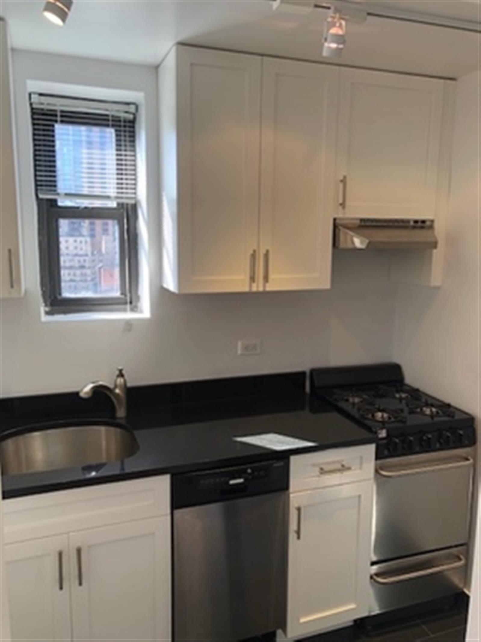 a kitchen with granite countertop a sink a stove and cabinets