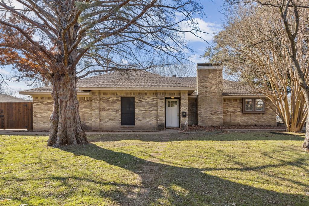 a front view of a house with a yard and large tree