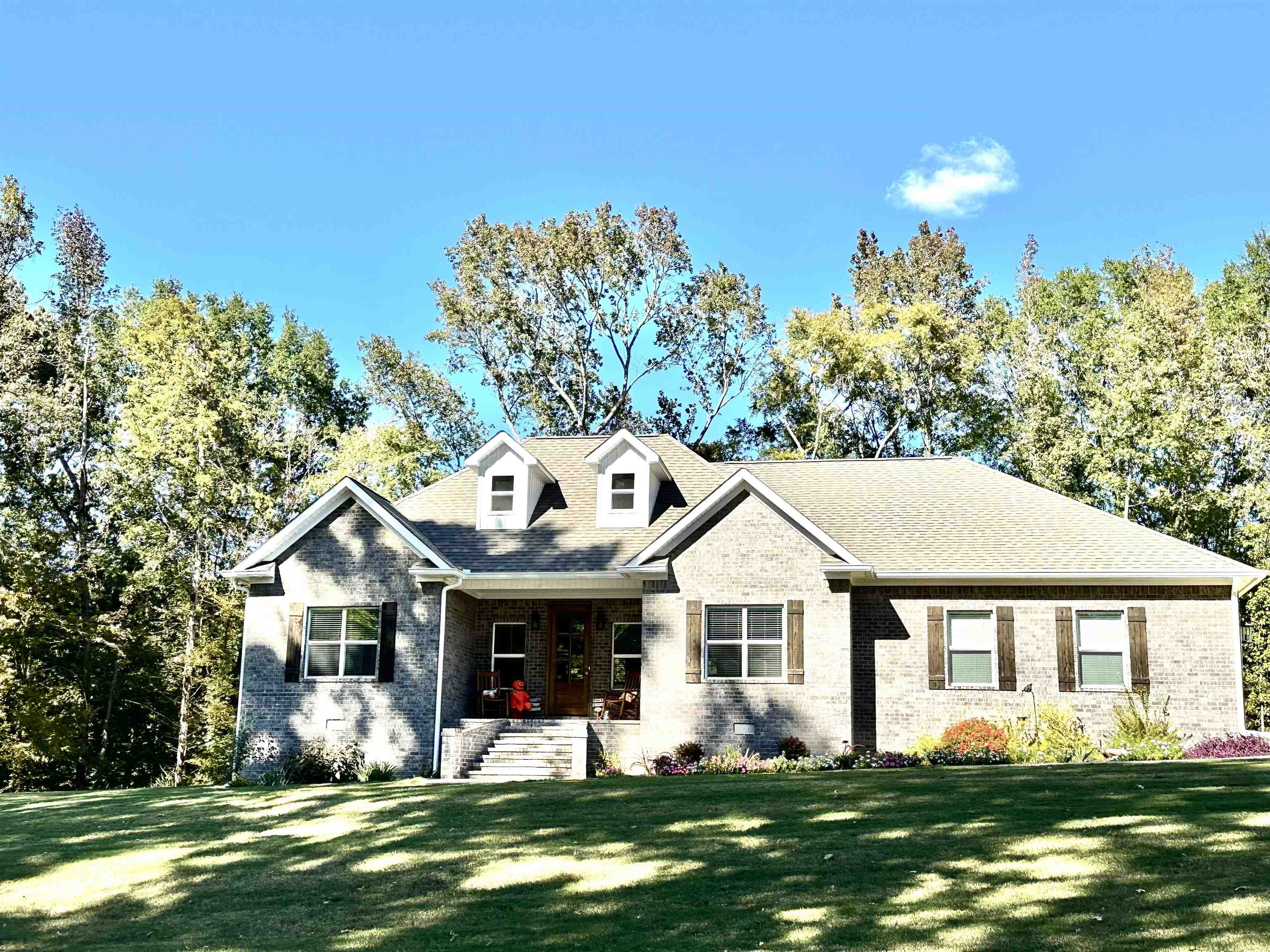 a front view of a house with a garden and trees