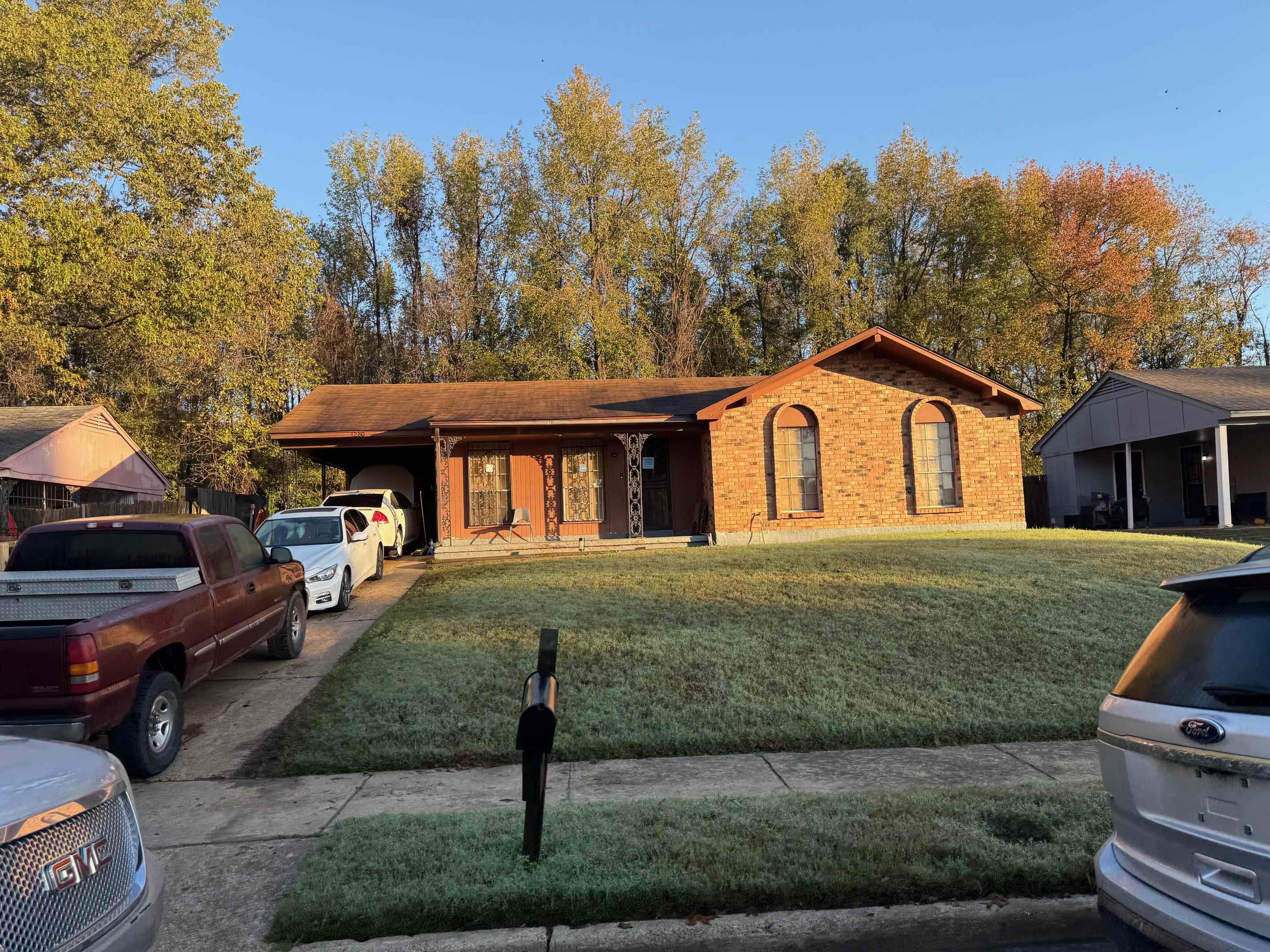 Ranch-style house featuring a carport and a front lawn