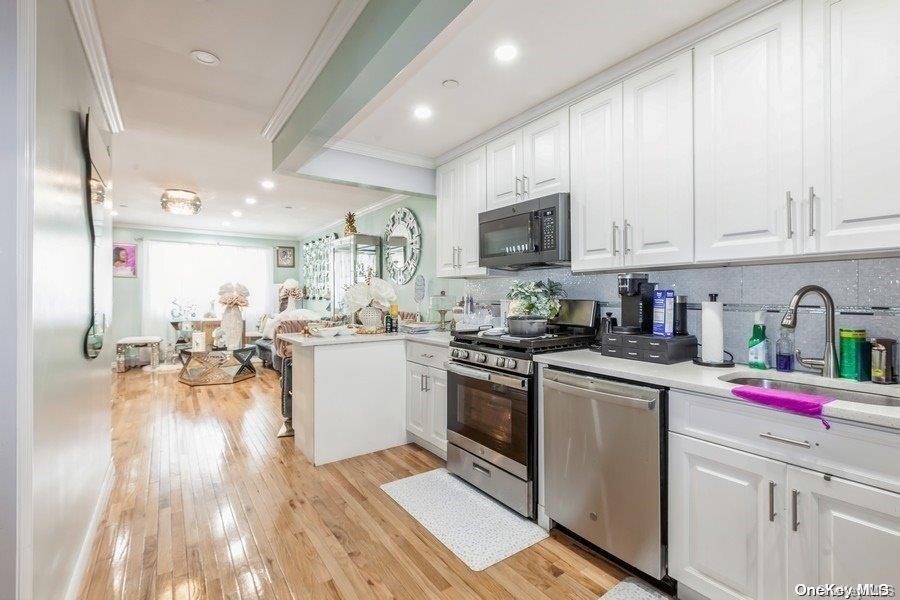 a kitchen that has a lot of white cabinets and stainless steel appliances