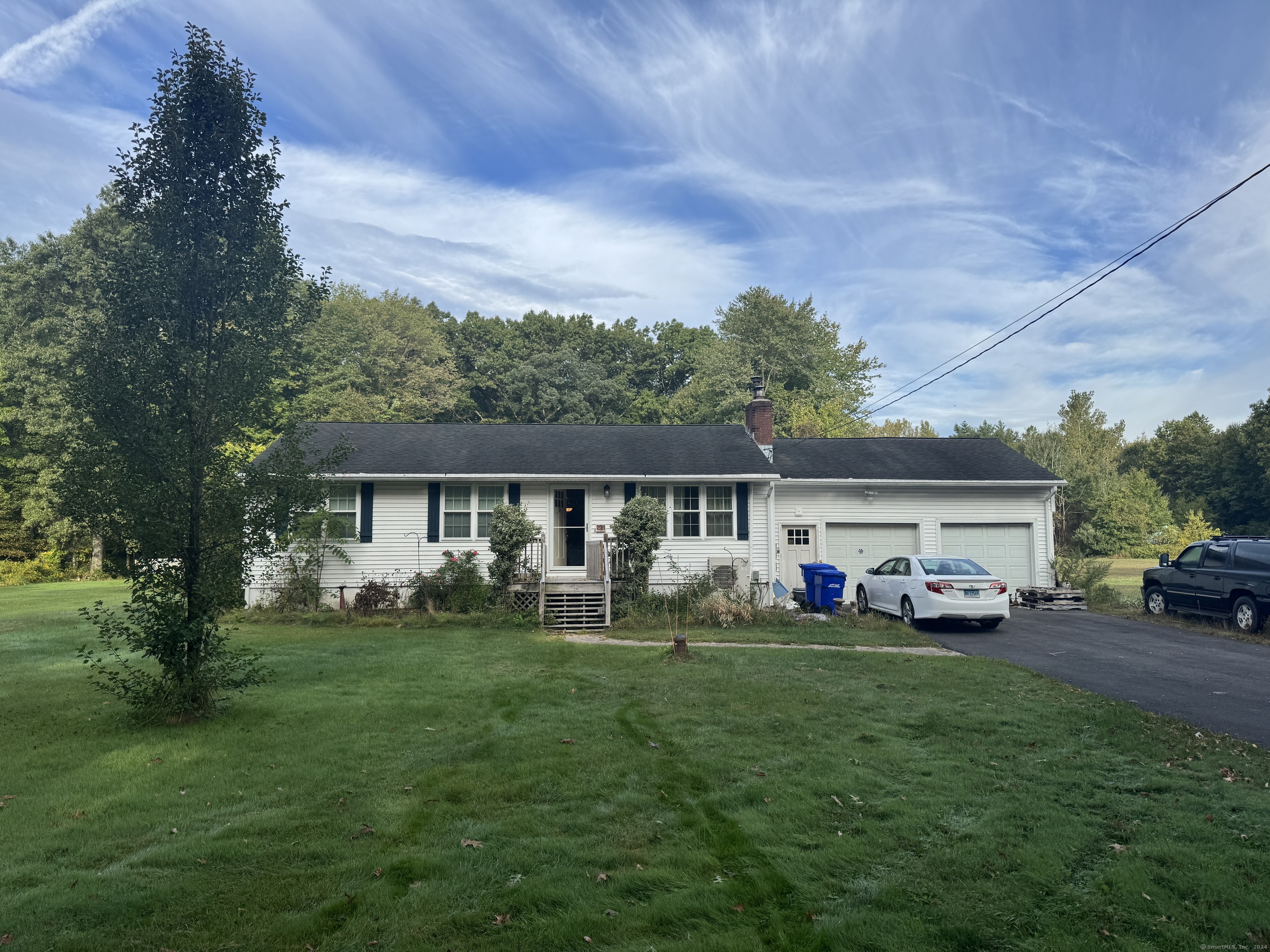 a front view of a house with a garden and trees