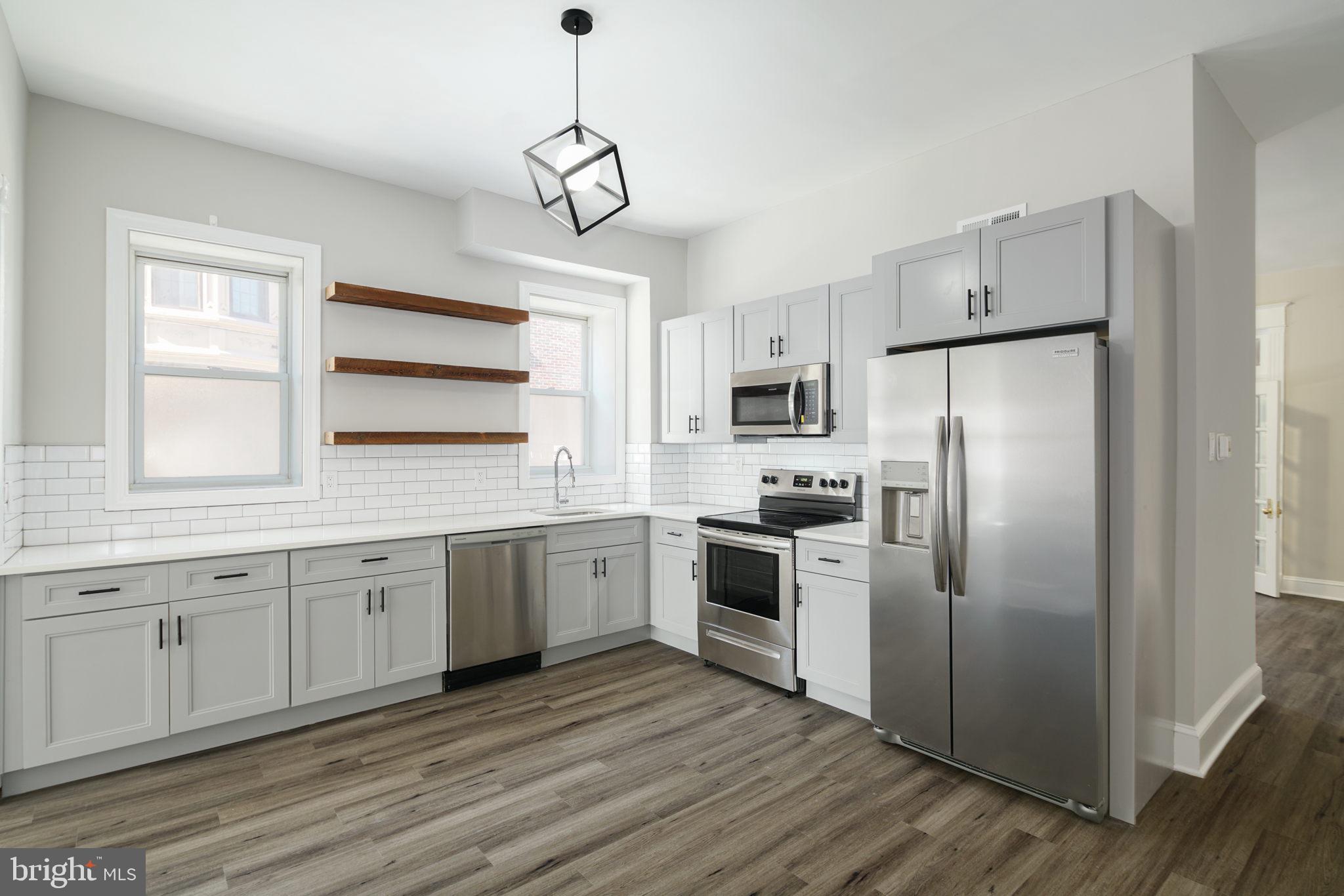 a kitchen with cabinets stainless steel appliances a sink and a window