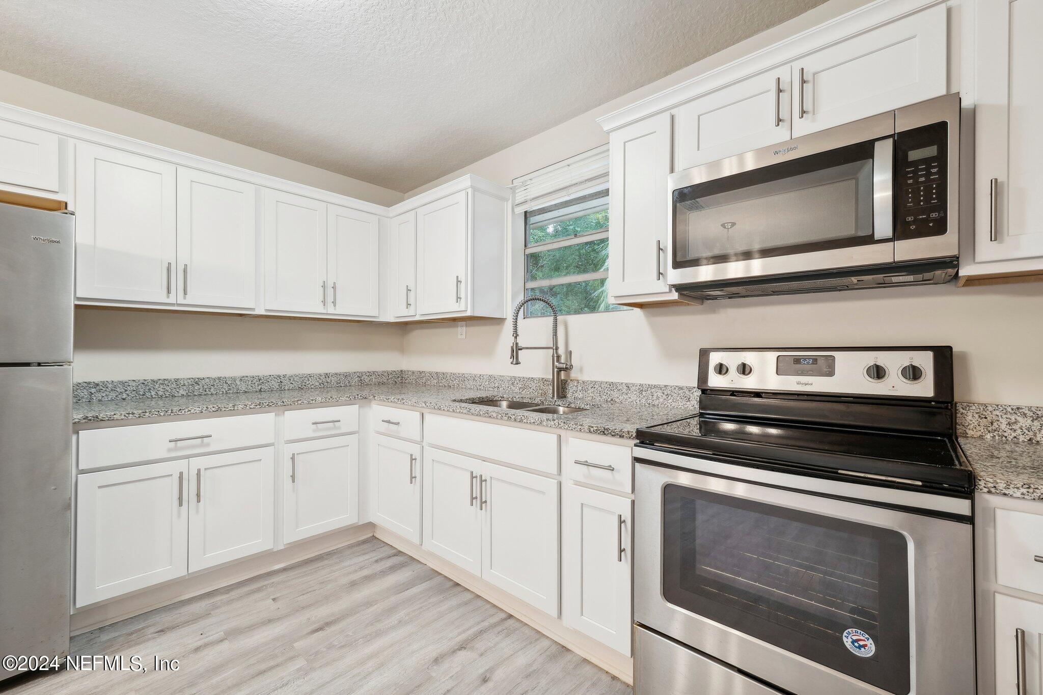 a kitchen with granite countertop a stove microwave and sink