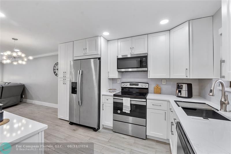 a kitchen with a sink stainless steel appliances and white cabinets