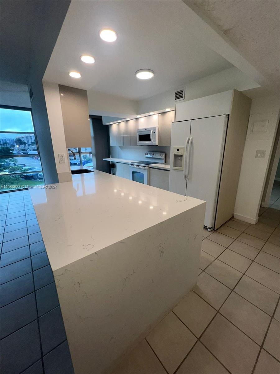 a large kitchen with a sink a refrigerator and a stove top oven