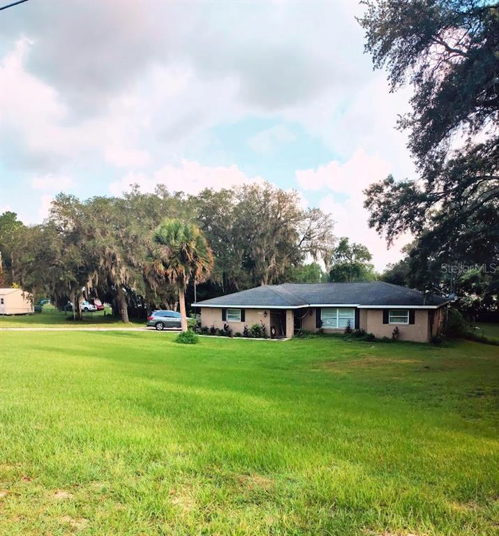 a view of a house with a big yard and large trees