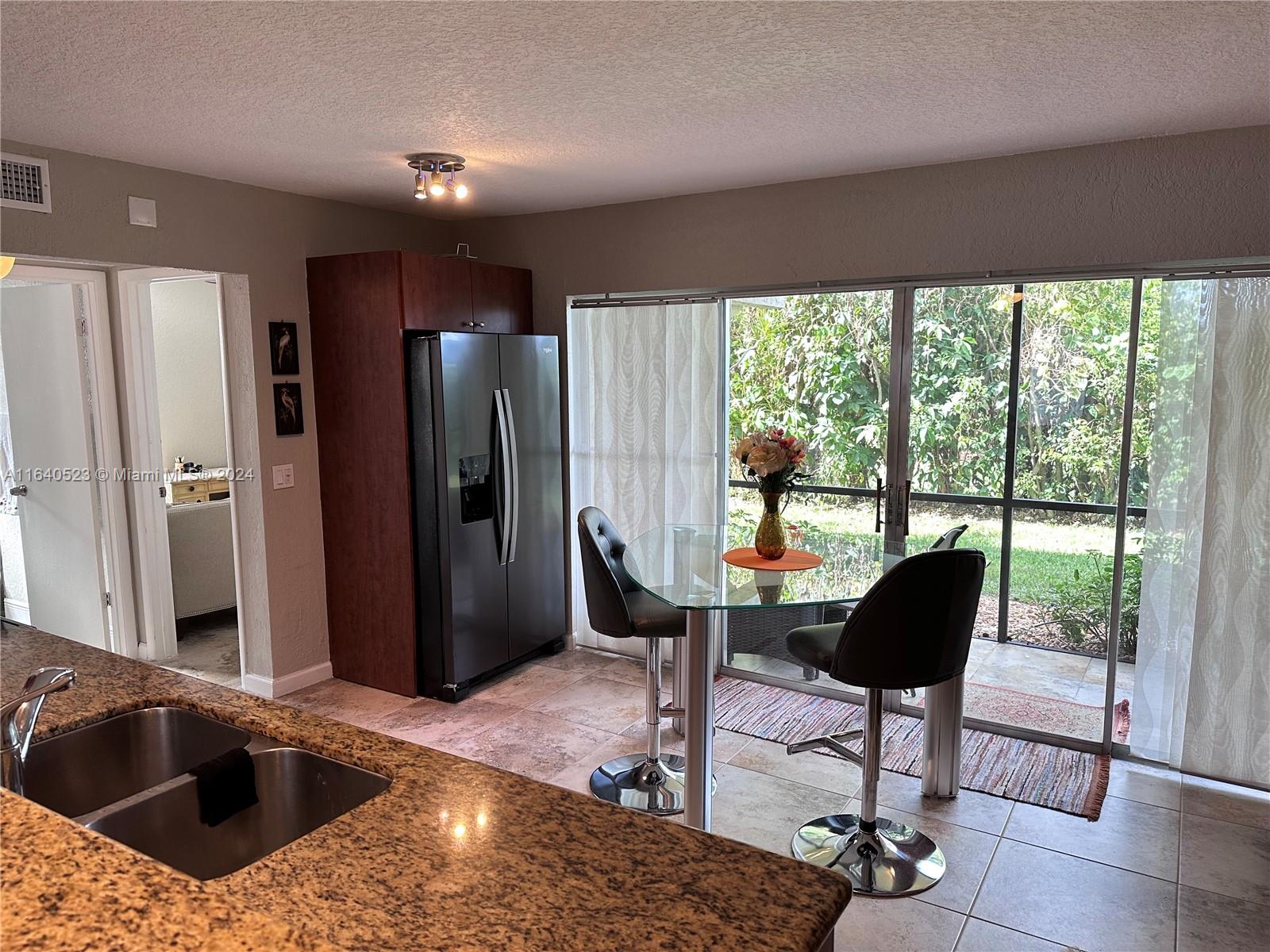 a kitchen with stainless steel appliances kitchen island granite countertop a refrigerator and a sink