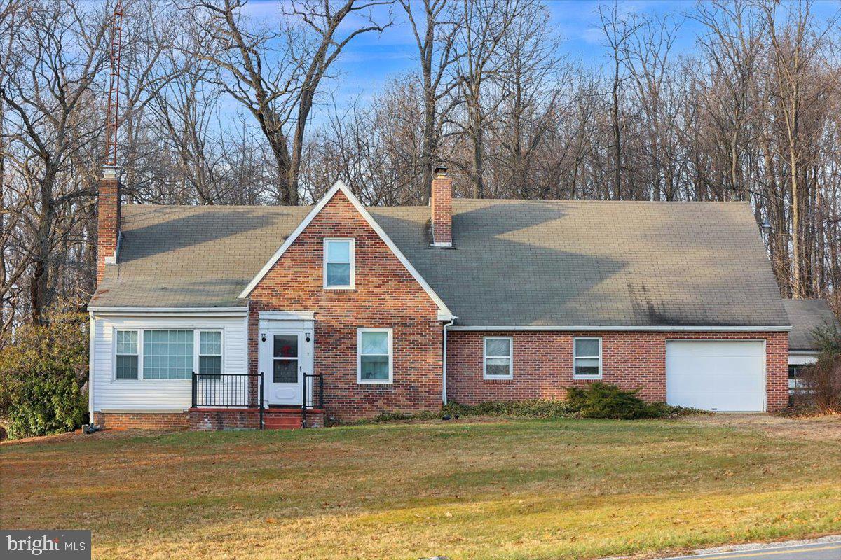 a view of a house with a yard and large tree