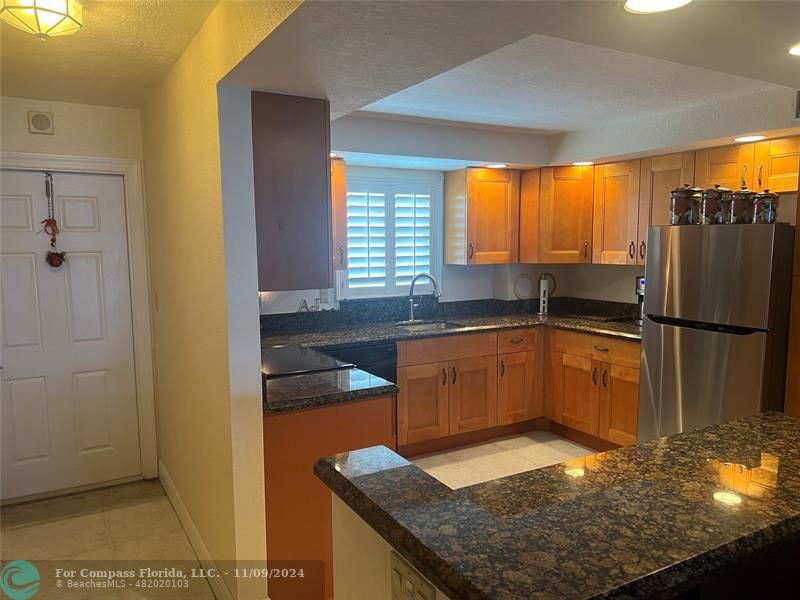 a kitchen with granite countertop a sink and a refrigerator