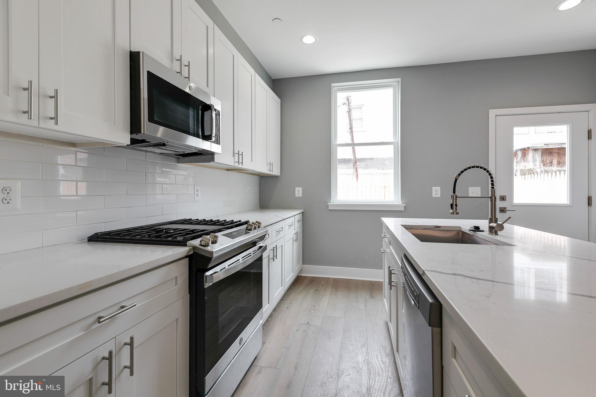 a kitchen with stainless steel appliances kitchen island a sink stove top oven and cabinets