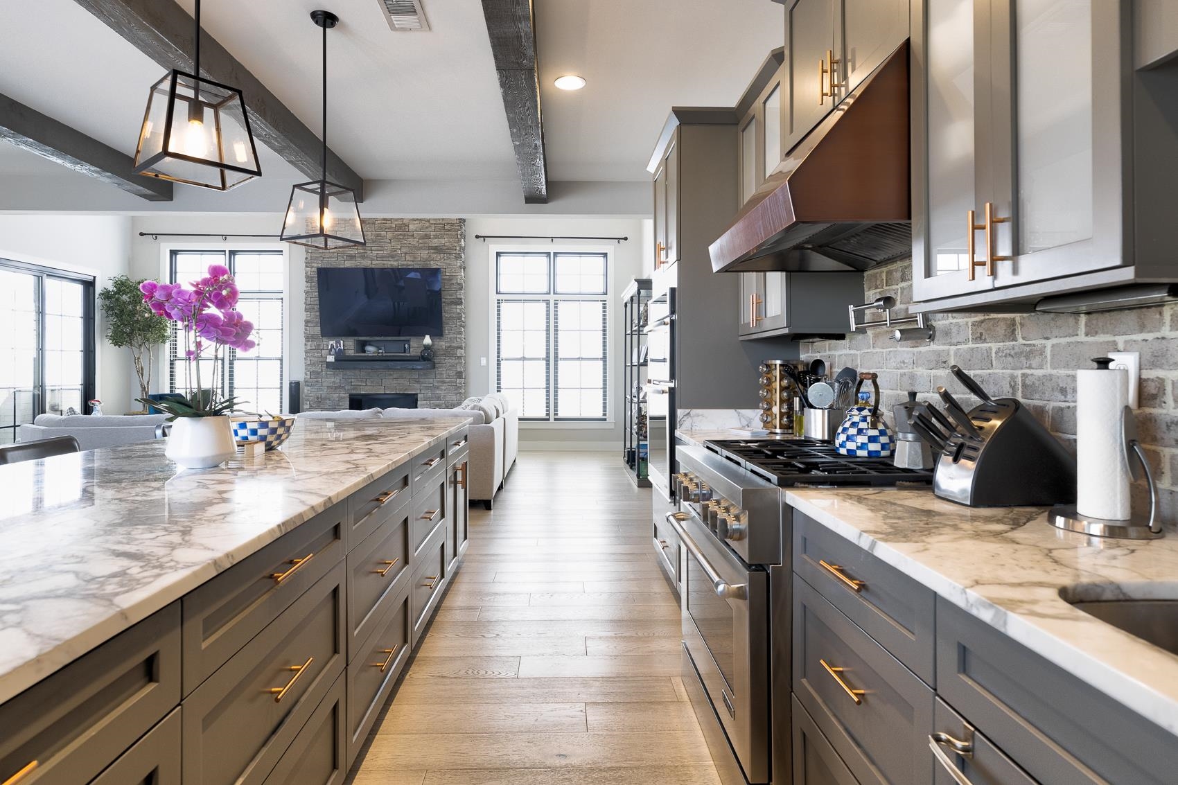 Kitchen featuring high end range, beamed ceiling, light wood-type flooring, and a wealth of natural light