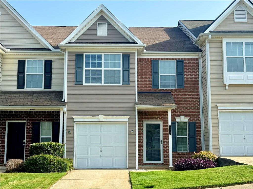 a view of a brick house with many windows and a yard