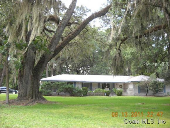 a view of a big yard with a house and large trees