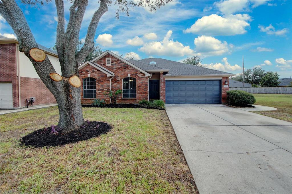 a front view of a house with a yard and large tree