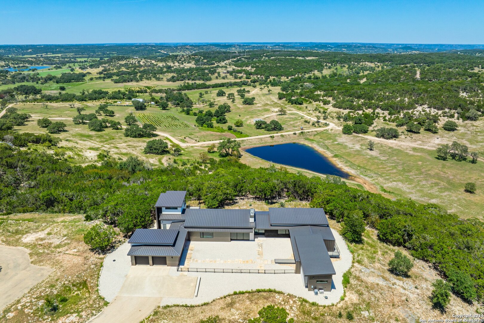 an aerial view of residential houses with outdoor space and trees all around