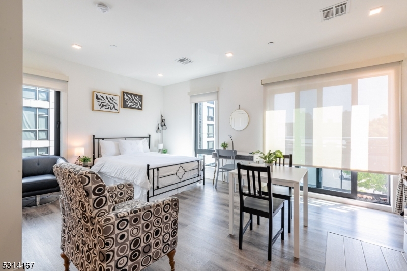 a bedroom with furniture wooden floor and a large window