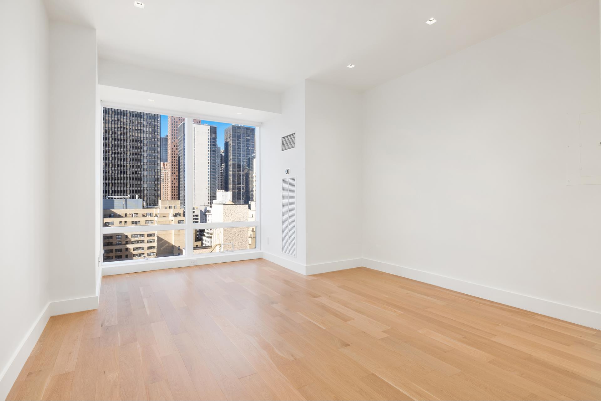 an empty room with wooden floor and floor to ceiling window