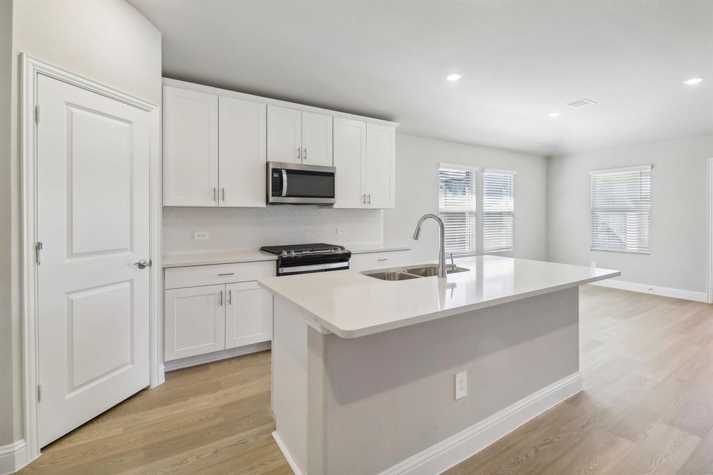 a kitchen with stainless steel appliances a sink a stove a microwave and cabinets