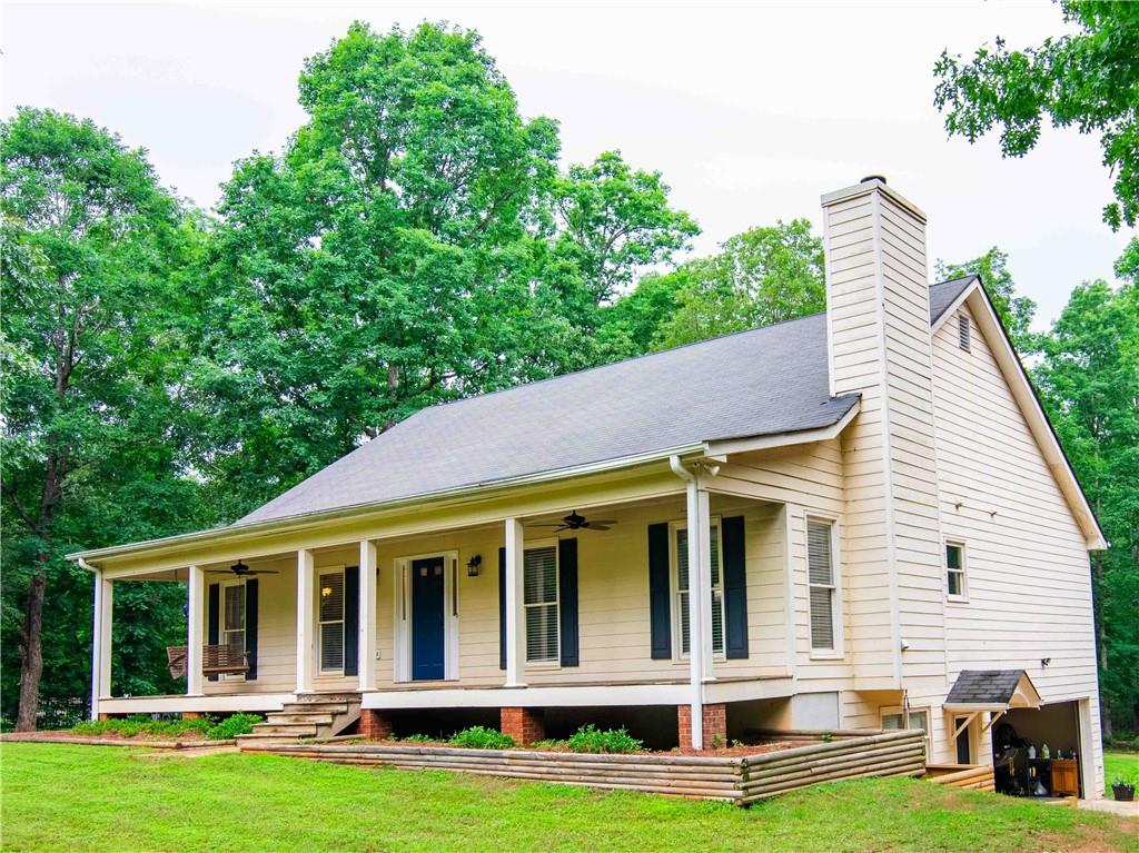 a view of a white house with large windows and a yard with plants