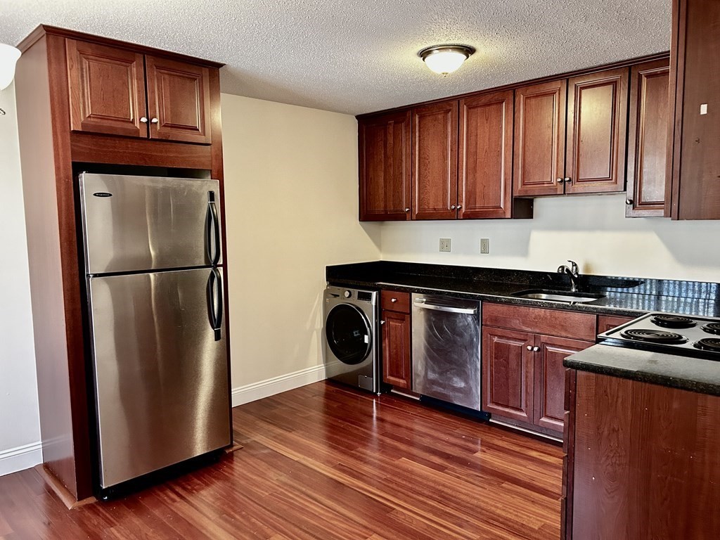 a kitchen with granite countertop wooden floors stainless steel appliances and cabinets