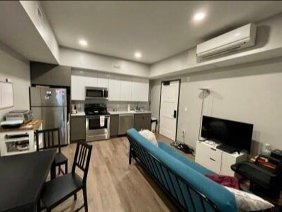 a large living room with stainless steel appliances furniture a flat screen tv and a view of kitchen