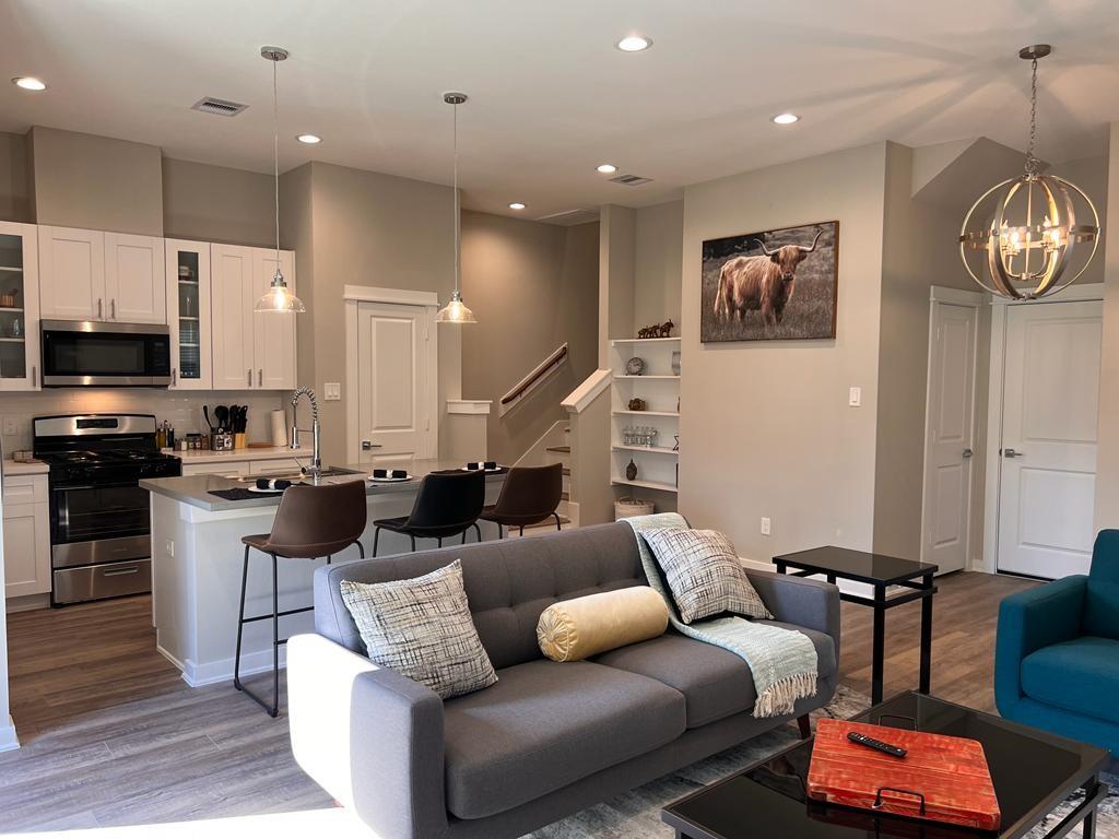 a living room with furniture kitchen view and a wooden floor