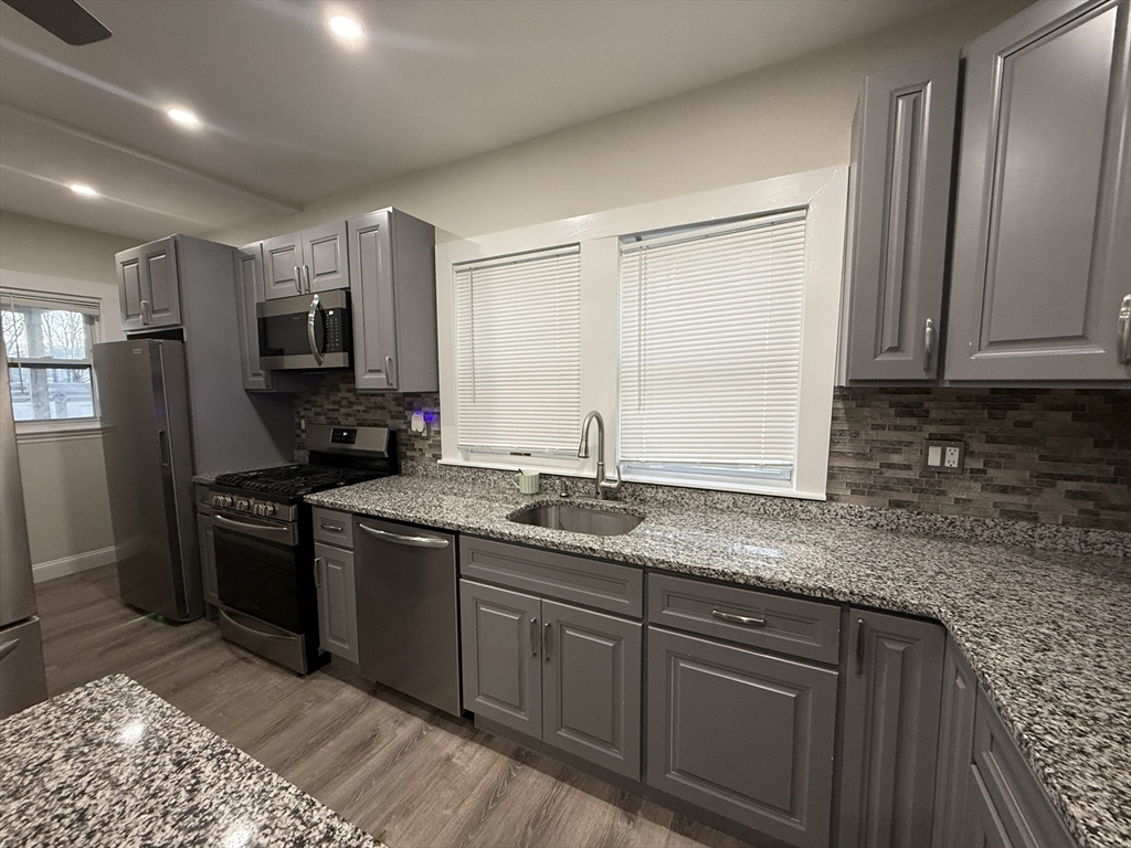 a kitchen with stainless steel appliances granite countertop a sink stove microwave and refrigerator