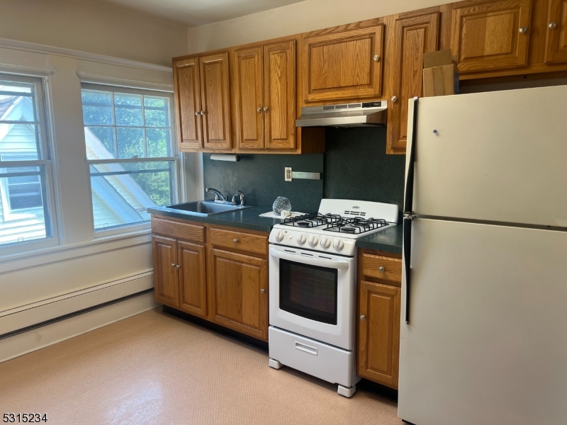 a kitchen with granite countertop a refrigerator stove and cabinets