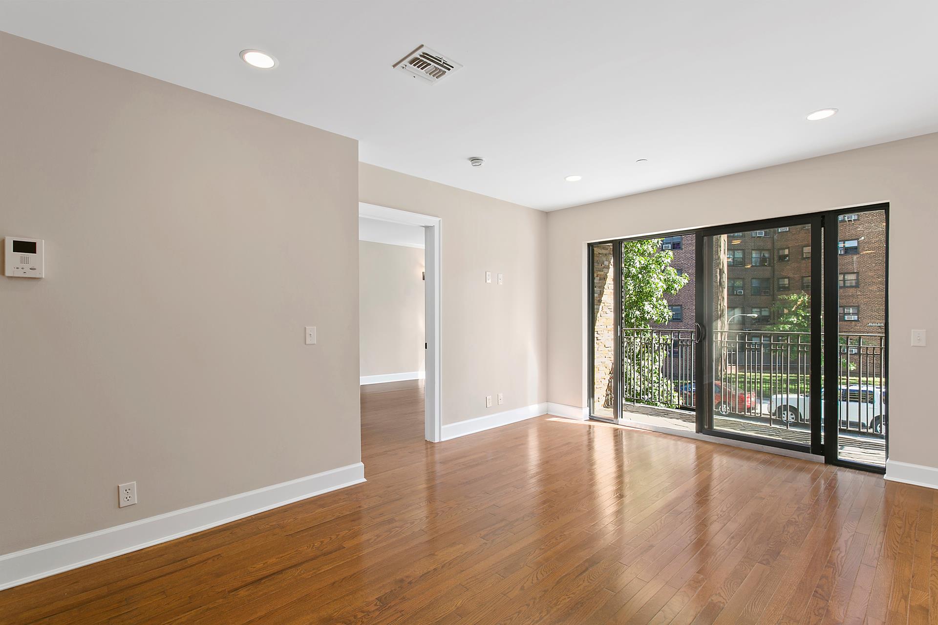 a view of an empty room with wooden floor and a window