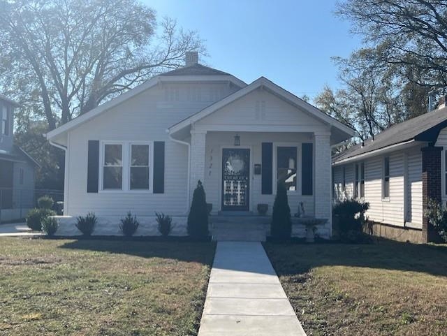 Bungalow with a porch and a front lawn