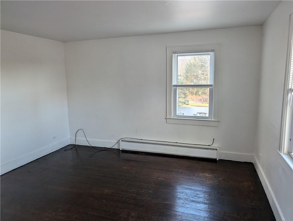 Spare room with a baseboard radiator and dark hardwood / wood-style flooring