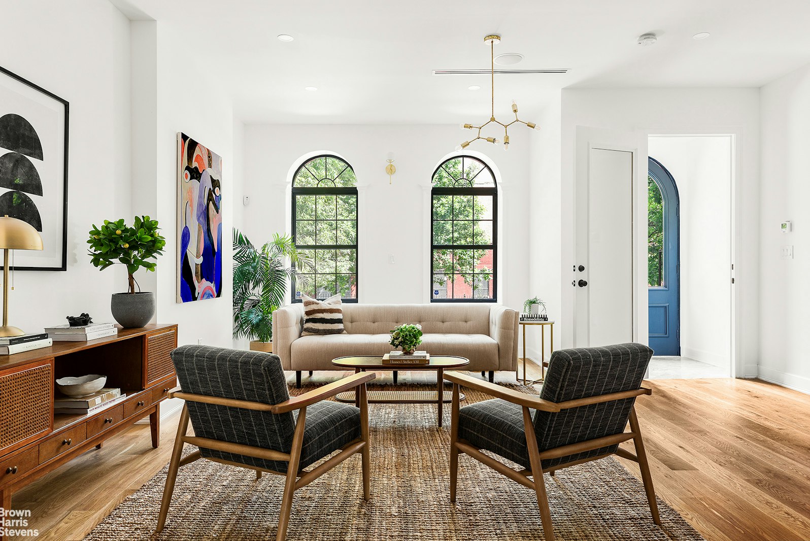 a living room with furniture a chandelier and a large window