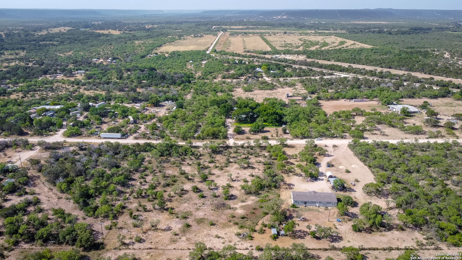 an aerial view of residential houses with outdoor space and trees