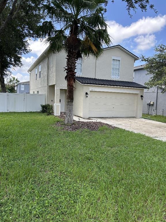 a view of a house with a big yard plants and large tree