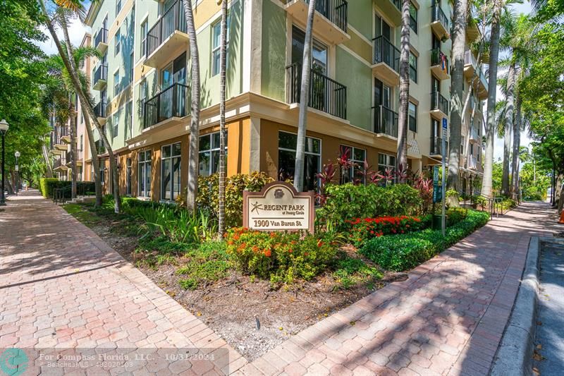 a front view of a multi story residential apartment building with yard and green space