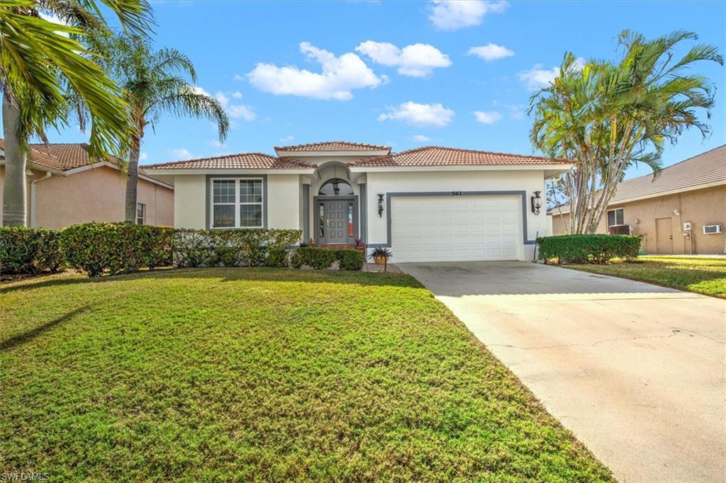 Mediterranean / spanish-style house with a garage and a front lawn