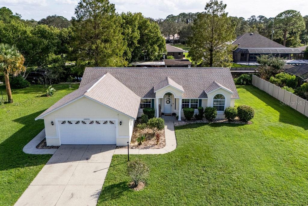 a aerial view of a house with a yard and table and chairs under an umbrella