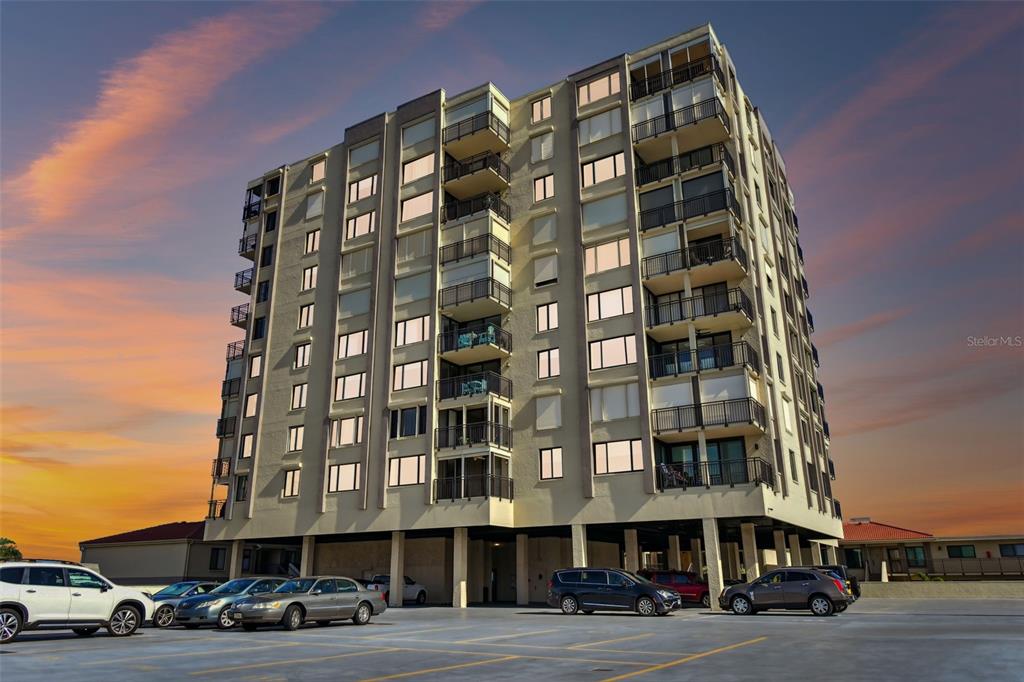 a front view of a building with lot of cars and trees