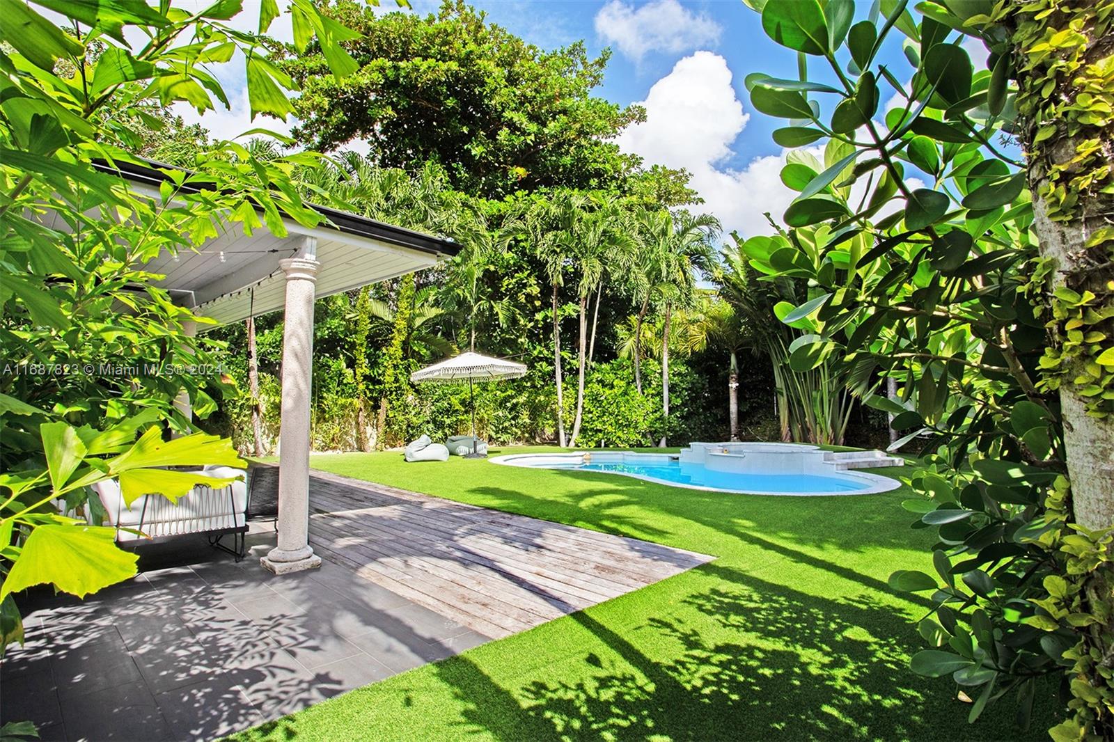 a view of a backyard with table and chairs plants and large trees